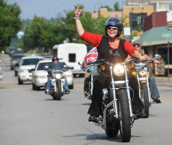 BIKES, BABES & BLING Theresa Radcliffe, originally from the north of England but now a Fayetteville resident, waves Friday as she rides down West Dickson Street aboard “Tallulah,” her motorcycle, during the Lady’s Parade of Power of the Bikes, Babes & Bling motorcycle rally in Fayetteville. “I don’t know what they did to make Bikes, Blues & BBQ so big, but they need to do it for this,” Radcliffe said. The event, which is in its second year, features music, a clothing swap meet, a scavenger hunt, karaoke, a bike show, group rides, live music and a Dickson Street pub crawl. For more information, go online to bikesbabesandbling.com.
