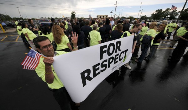 Guillermo Ruiz of Dallas holds a sign Thursday as members of the groups Making Change at Walmart and Organization United for Respect at Walmart gather around Walmart representatives outside the company’s home office.
