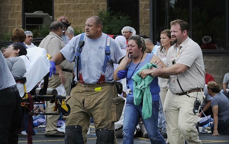 An employee at the Tyson Plant on Berry Street in Springdale is helped by another employee and emergency personnel to a waiting ambulance after being exposed to chlorine gas on Monday. About 300 employees were evacuated from the plant because of the chemical accident, and officials said more than 150 employees were taken to area hospitals. For additional photos, go to <a href="http://photos.nwaonline.com">photos.nwaonline.com</a>.