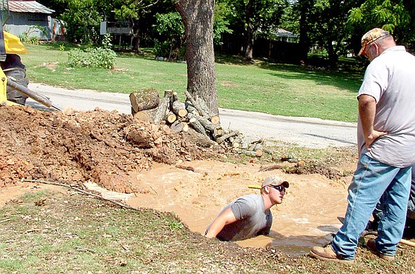Sy Kirby, left, and Michael Nida, right, were two of the Pea Ridge Water Department employees working Tuesday morning to isolate and stanch a water leak created by a SWEPCO employee puncturing a water line. The city is under a boil order until further notice.