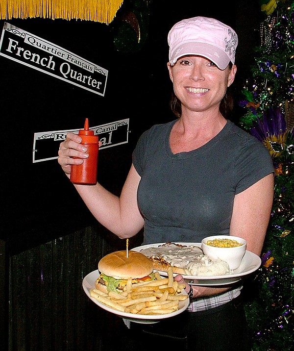 Chara Sullins, server at Fleur de Lis Grill in Gentry, carries plates of food to lunch guests on Friday.
