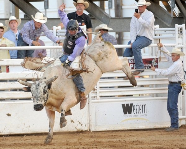 Luke Dotson, of Hindsville, rides Keeper Saturday during the Buckin' in the Ozarks Professional Bull Riders event at Parsons Stadium in Springdale. Dotson led the field after first round of competition. 