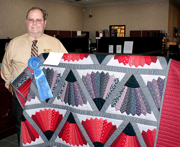 Kiwanis club member Rickie Stark with the prize winning quilt the club will give away on Gravette Day.
