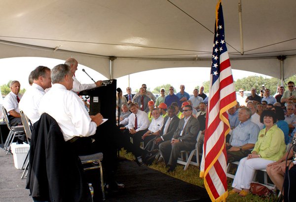 Commissioner Dick Trammel, at the mike, was emcee for the highway groundbreaking ceremony at Hiwasse Friday. Among those on the podium, from the right, are, Transportation Secretary Ray LaHood, U.S. Senator Mark Pryor, and Arkansas Governor Mike Beebe. Area State Representative Mary Lou Slinkard, Gravette, is sitting to the right of the American flag.
