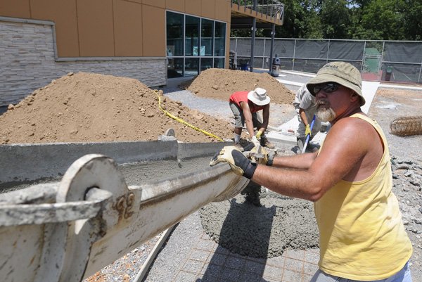 Ed Rush, right, owner of Rush Concrete, helps pour a concrete sidewalk Thursday, July 14, 2011, leading to the new Bella Vista Village's Kingsdale Tennis Center. There will be a ribbon cutting and open house celebration for the facility from 4 to 6 p.m. on July 28.
