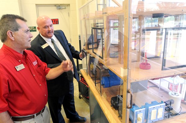 Henry Shifflet, left, NorthWest Arkansas Community College weather trainer, and Rick Mayes, NWACC director of Building Services, look into a pressure house Monday before the opening of the college’s Weatherization Training Center in Bentonville. The program trains workers to provide energy efficiency in homes and businesses in new construction.