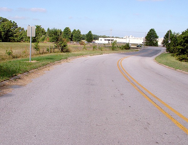 Trucks using this Arkansas Highway 59 spur sometimes are blocked by a train parked on the tracks and back out onto the main highway. Being discussed is the purchase of land to the left of the spur for a truck turnaround.
