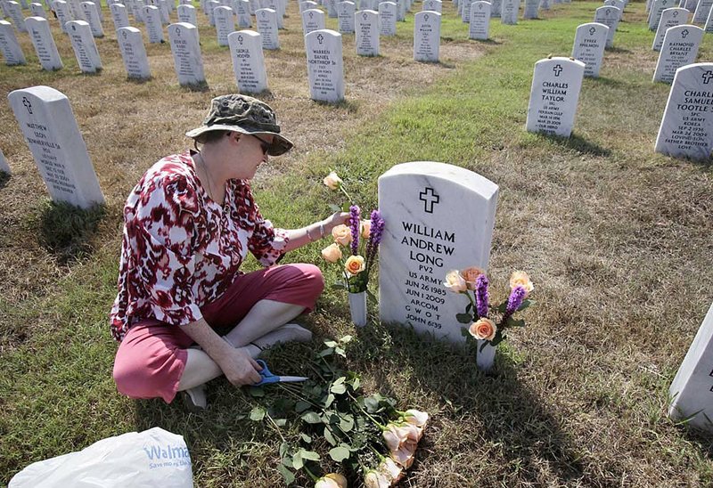 Janet Long, mother of slain Army Pvt. William Andrew Long, places flowers on her son’s grave Saturday at the Arkansas Veterans Cemetery in North Little Rock.  Abdulhakim Muhammad pleaded guilty Monday to charges of capital murder and attempted capital murder in the 2009 shooting that killed Pvt. Long.
