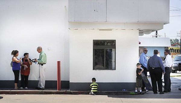 A Rogers Police investigator interviews witnesses Monday at the Superstop on Eighth Street and New Hope Road after a police officer was involved in a shooting there.