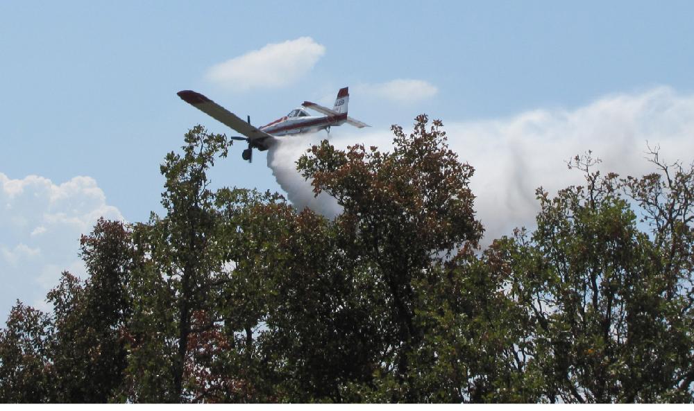 Arkansas Democrat-Gazette/DAVE HUGHES

A private plane under contract with the Arkansas Forestry Commission drops a
load of water on a grass fire south of Norwood Drive in Greenwood about noon
Tuesday. The fire that started Thursday continues to rekindle in hot, dry
and windy conditions despite efforts to extinguish it.8/2/11