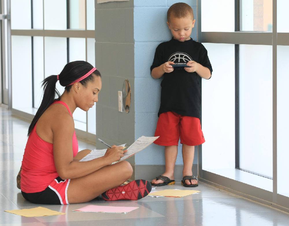 Arkansas Democrat-Gazette/fSTATON BREIDENTHAL 8/2/11
Kingston Alexander (right), 4, plays an electronic game Tuesday morning at Dr. Don R. Roberts Elementary School while his mother, Jewell Alexander, completes paperwork during Little Rock School District check-in for the upcoming school year. Check-in continues today from 10 a.m to 7 p.m.