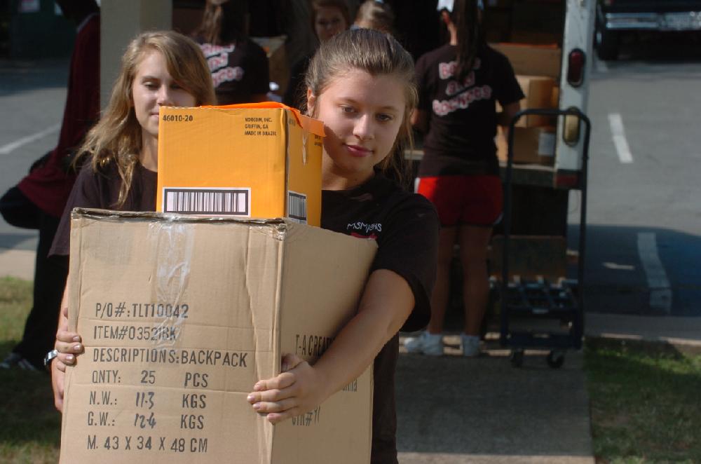 Arkansas Democrat-Gazette/STEVE KEESEE 7/28/11 Volunteer, Lexie Sadler, a member of the Mount St. Mary Academy cheerleading squad , helps to unload a truck Thursday filled with school supplies that the Junior League of Little Rock is donating to students in need at Little Rock School District's Romine Elementary, one of six district schools receiving the items . The JLLR program called Stuff the Bus began five years ago with the goal of adding one LRSD elementary a year.