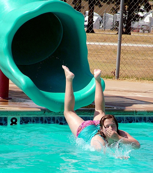 Nikki Lester hits the water after coming off the slide at the McKee Foods pool Saturday. Those who took part in the summer reading program at Gentry Public pool Library enjoyed a pool party, inflatable rides and hot dogs.
