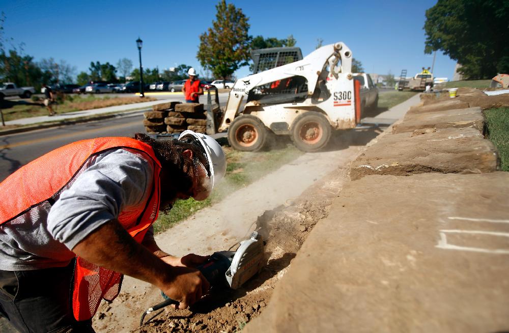 Arkansas Democrat-Gazette/JASON IVESTER --09/06/11--
Cody Hale with Mayes Masonry LLC of Goshen grinds numbers into rocks that form the wall along Dickson Street next to the lawn outside Old Main on the Fayetteville campus of the University of Arkansas on Tuesday, Sept. 6, 2011. The numbers, which will not be visible when the rocks are replaced, help keep the order so that the rocks are returned to the same positions after construction. A portion of the wall boundry is being temporarily removed to make way for a temporary construction road.