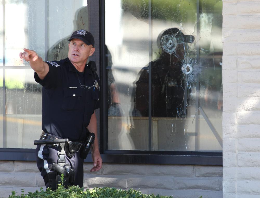 With bullet holes seen in a window, officers look for evidence at the scene of a shooting at an IHOP restaurant in Carson City, Nev. on Tuesday, Sept. 6, 2011. Seven people were wounded after a gunman opened fire at the restaurant, authorities said. (AP Photo/Cathleen Allison)
