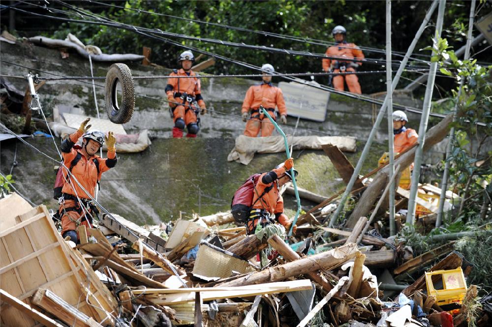Firefighters pull debris looking for missing people at Gojo, central Japan, Tuesday, Sept. 6, 2011. Typhoon Talas dumped record amounts of rain on central and western Japan and lashed wide swaths of the country with destructive winds before being downgraded to a tropical storm. (AP Photo/Kyodo News) JAPAN OUT, MANDATORY CREDIT, NO LICENSING IN CHINA, FRANCE, HONG KONG, JAPAN AND SOUTH KOREA