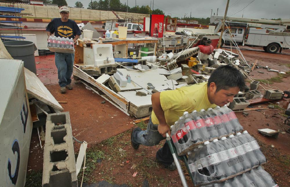 Matias Gomez, left, and Jeronemo Ramirez, right, move food and perishables out of the destroyed concession stand at the Dixie Speedway in Woodstock, Ga., Tuesday, Sept. 6, 2011. Volunteers and workers began clean up at the speedway where damage was extensive and the massive bleachers on turn-one were thrown into a steel heap. Meteorologists from the National Weather Service confirmed a tornado with maximum winds of around 90 miles per hour touched down Monday just south of the Dixie Speedway. (AP Photo/The Atlanta Journal-Constitution, John Spink)
