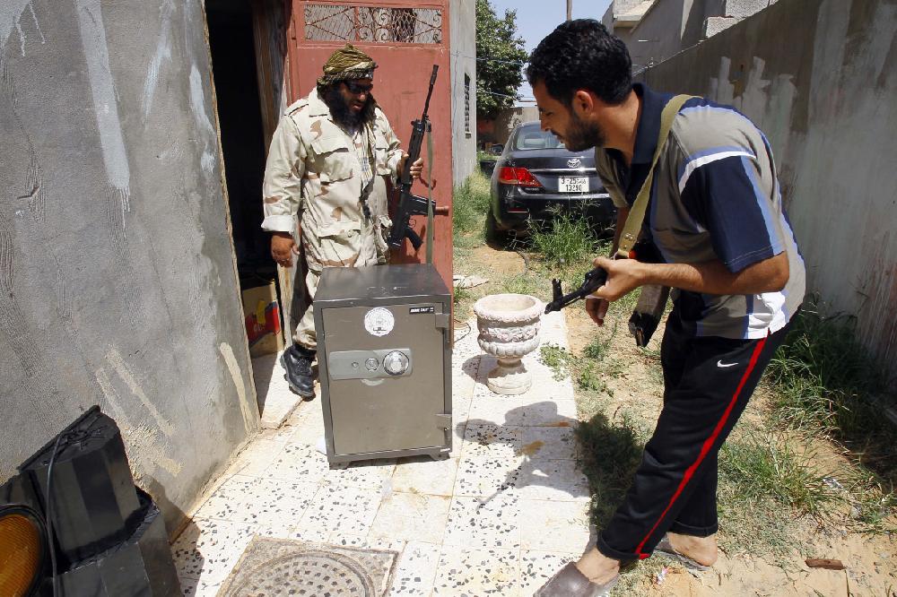 Libya rebel local military chief and mosque preacher Sheikh Hussein Furjani, left, finds a looted safe during a raid to find illegal weapons and belongings of suspected Gadhafi supporters in Khalet El Furjan district in Tripoli, Libya, Tuesday, Sept. 6, 2011. Rebel fighters burst into various houses of suspected Gadhafi supporters, searching rooms and hauling away military uniforms, a looted safe and documents linking homeowners to the former regime. (AP Photo/Francois Mori)