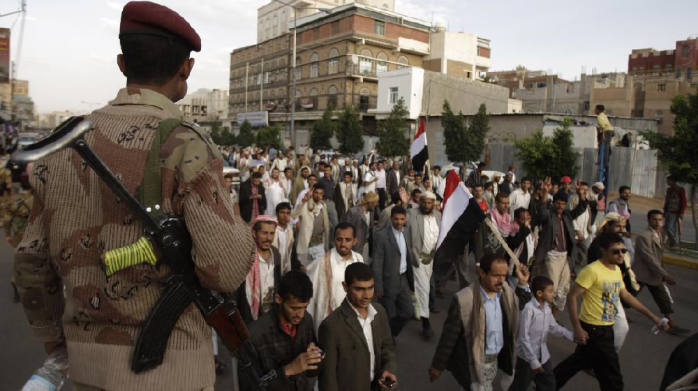 A defected army soldier, left, stands guard at a street where protestors march during a demonstration demanding the resignation of President Ali Abdullah Saleh, in Sanaa, Yemen, Tuesday, Sept. 6, 2011.(AP Photo/Hani Mohammed)