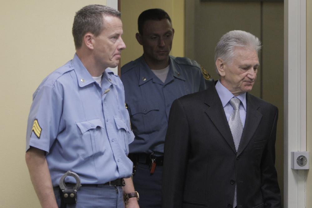 Momcilo Perisic, the former chief of staff of the Yugoslav army, right, enters the court room of the Yugoslav War Crimes Tribunal in The Hague, to hear the verdict of the court Tuesday Sept 6, 2011. Prosecutors accused Perisic of providing crucial aid to Bosnian Serb forces that allowed them to carry out atrocities including the 1995 massacre of 8,000 Muslim men at Srebrenica and the four-year siege and campaign of shelling and sniping targeting Sarajevo. (AP Photo/Peter Dejong, Pool)