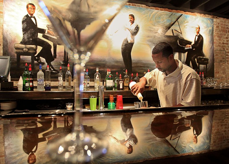 Nicholas Guy, general manager of Porter’s Jazz Cafe in Little Rock, mixes drinks for lunch customers Wednesday. 