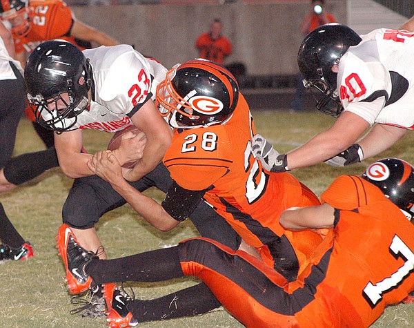 Gravette's Logan Hirsh (28) and Chase Brody (7) bring down McDonald County's Chad Roark (23) in play at Gravette on Friday.