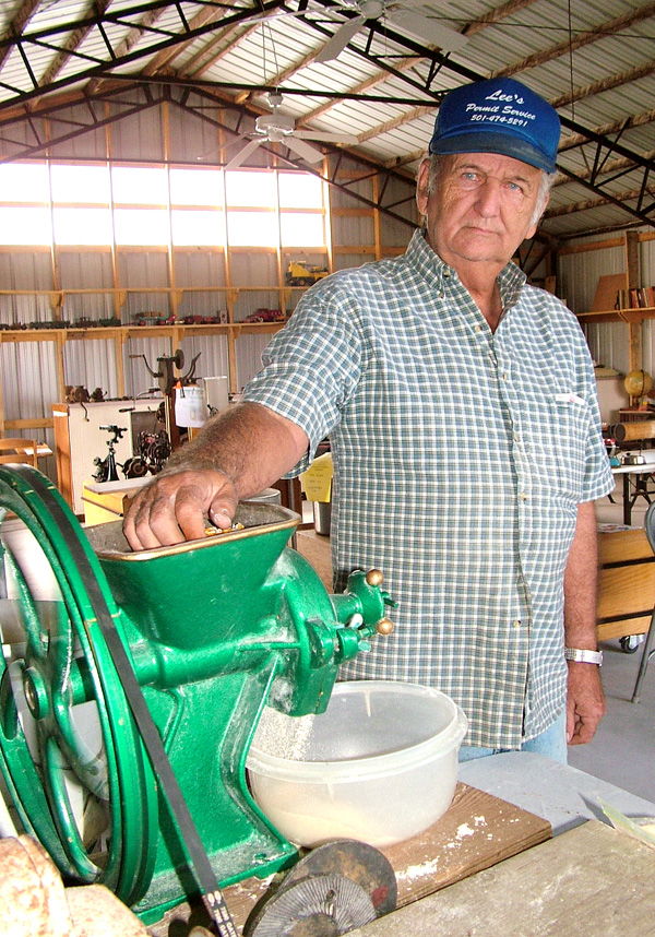 Carl Wood, of Gentry, grinds corn in the antique household items building at the Tired Iron of the Ozarks fall show on Friday. The cornmeal can then be used for baking.