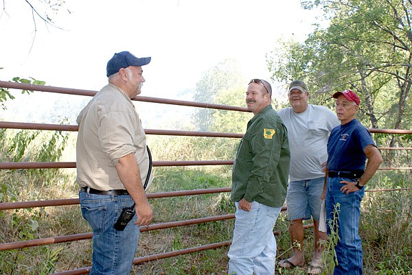 With heavy smoke obscuring the hills and trees in the background, fire officials discussed and monitored the 700-plus-acre blaze northeast of Sulphur Springs last week. Air as far south at Gravette was filled with varying amounts of smoke during the several-day fire which blackened the rough, hilly, scantily-settled terrain. George Stowe-Rains, second from left, said the blaze was contained in an area in which no persons or structures were threatened and the plan was to let the fire burn itself out and clear undergrowth and allow the forested area to re-estblish itself. Others in the photo are, from the left, Charley Orr, Asst. Fire Chief at Sulphur Springs; John Varner, Sulphur Springs Fire Chief, and Will Hanna, Benton County Fire Marshal.
