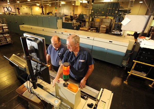Bill Ogryzek, left, and Eddie Samuels, both electronics technicians for the Postal Service, perform preventive maintenance Friday on a sorting and labeling machine before mail sorting begins at the postal facility in Fayetteville.

