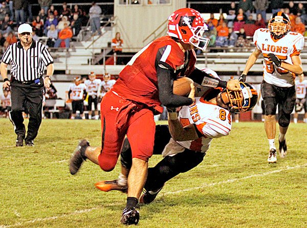 Gravette's Adam Roberts gets face masked by a Poteau ball carrier during Friday night play in Oklahoma. Sam Riester, 35, heads for the action.