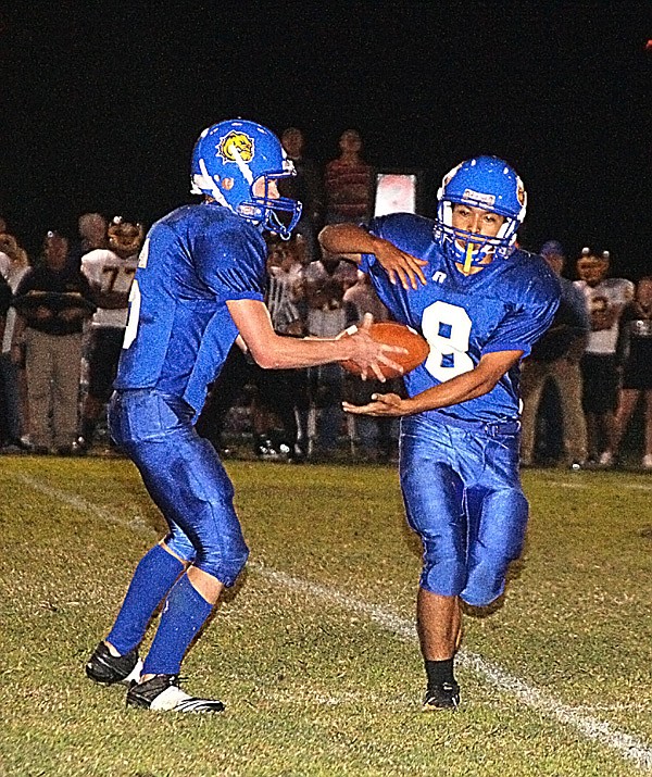 Decatur quarterback Evan Owens handed the ball off to running back Joe Castaneda during Friday's game against the Hackett Hornets.
