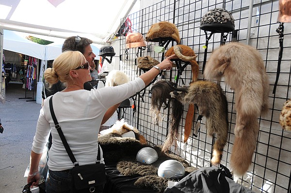 Deana Bastian looks at some helmets Wednesday at the Bikes, Blues & BBQ motorcycle rally on Dickson Street in Fayetteville. The helmets were created by Howling Helmets and were some of the more unusual items for sale at the rally.