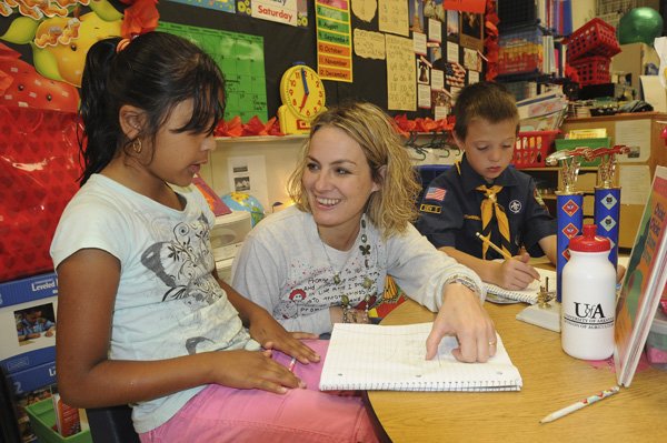 Susan Hill, a second-grade teacher at Jones Elementary School in Rogers, helps Jasimine Jimenez, left, and Alexis Pintor with a math lesson Friday.
