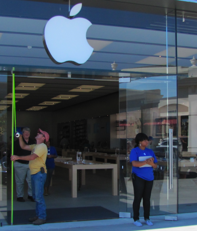 A worker measures the door at the Apple Store in Little Rock Thursday. Burglars broke through the glass entry late Wednesday night.