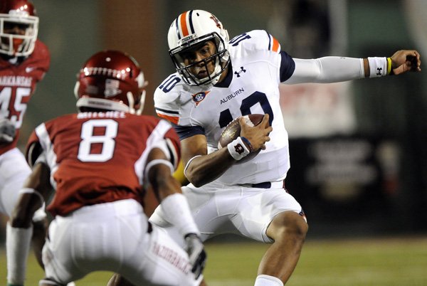 Auburn freshman quarterback Kiehl Frazier makes a cut to avoid Arkansas safety Eric Bennett during the Tigers’ game on Saturday against the Razorbacks at Reynolds Razorbacks Stadium in Fayetteville.