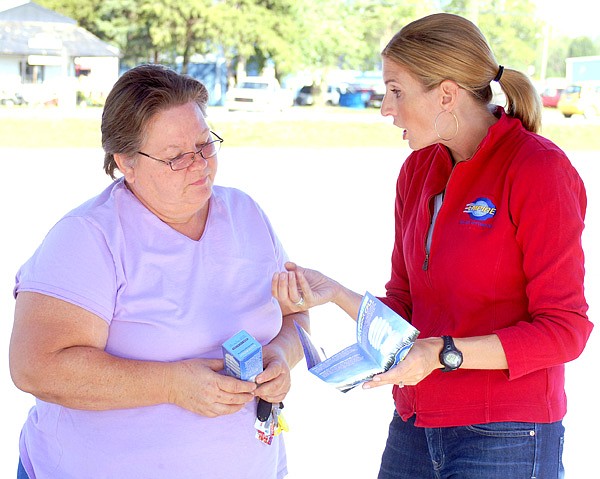 Lavern Golden, left, receives a compact florescent light bulb and a brochure about CFLs from Empire District employee Emily Stanley on Thursday. Empire District gave away complimentary CFLs and other energy-saving tips to their energy customers in Gentry on Wednesday to encourage them to use the energysaving bulbs and reduce their energy consumption and save on their electric bills.
