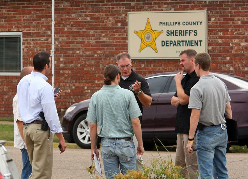 Law enforcement officers gather Wednesday morning outside the Phillips County sheriff’s office in Helena-West Helena, where things were quieter after Tuesday’s drug-trafficking raids. 