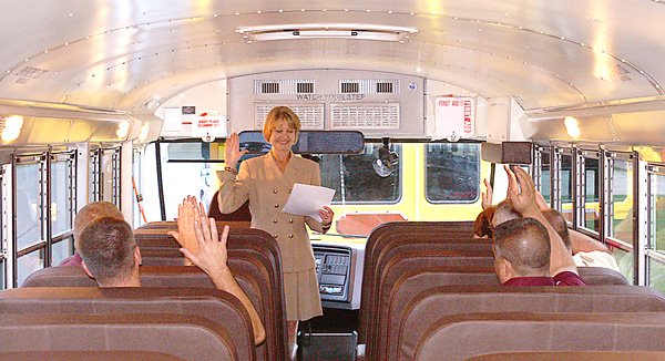 Benton County Clerk Tena O'Brien administers the oath of office to the elected members of the Gentry School Board Monday on board one of two new school buses recently received by the district.