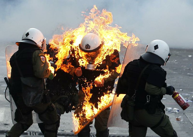 Greek riot policemen help a fellow officer who was hit by a firebomb Thursday in central Athens. 