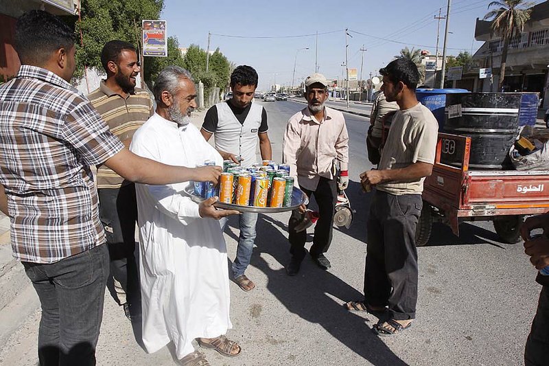 Abbas Fadel distributes juice Saturday in Barra, Iraq, to celebrate the announcement of the United States’ military withdrawal from that country. 