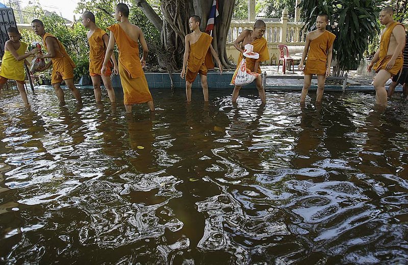Thai Buddhist monks use sandbags Saturday to try to protect Bangkok’s Weeru Wanaram temple from rising floodwaters. 