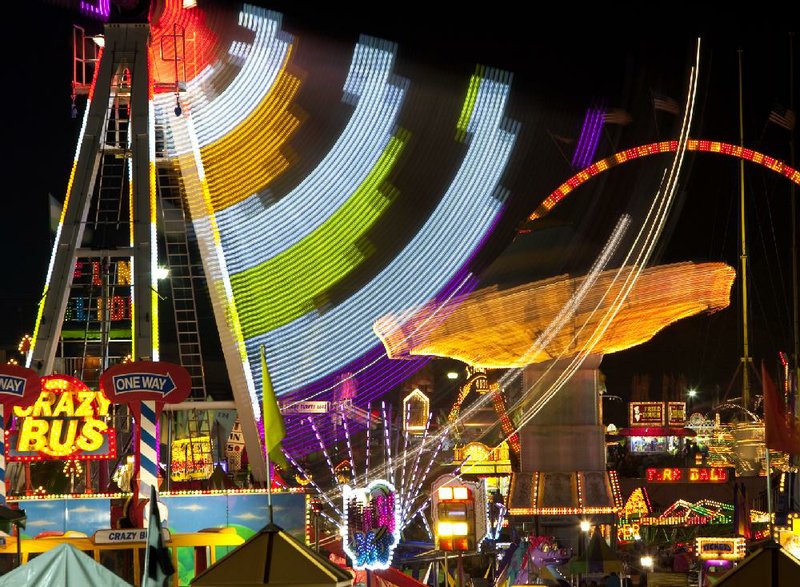 Carnival rides simultaneously twirl Sunday, which was the last night of the Arkansas State Fair. 