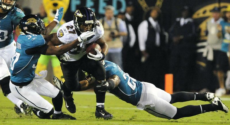 Jacksonville defenders Drew Coleman (left) and Dwight Lowery tackle Baltimore Ravens running back Ray Rice during the Jaguars’ 12-7 victory Monday night in Jacksonville, Fla. The Jaguars held the Ravens to 146 yards on offense. 