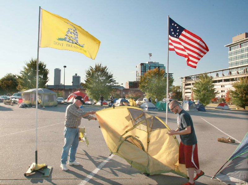 Occupy Little Rock participants Rob MacGregor (left) and Jason Bliss pitch a tent in a city-owned parking lot on Ferry Street after they and fellow protesters agreed to move from a park just west of the Clinton Presidential Center. 