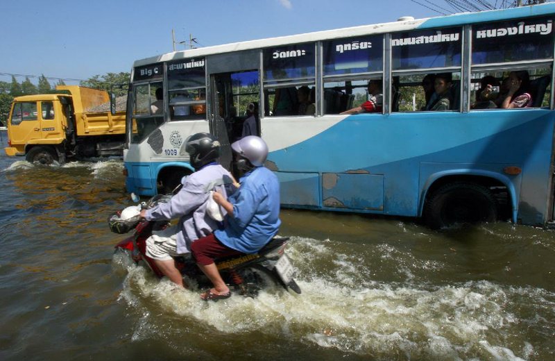 Motorists make their way along a flooded road Tuesday near Don Muang Airport in Bangkok. 