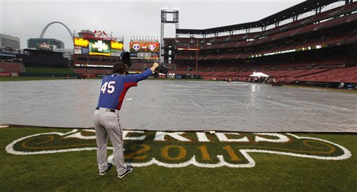 Texas Rangers' Derek Holland yells across a covered infield at Busch Stadium Wednesday, Oct. 26, 2011, in St. Louis, after officials announced that Game 6 of baseball's World Series is postponed due to rain. (AP Photo/Paul Sancya)