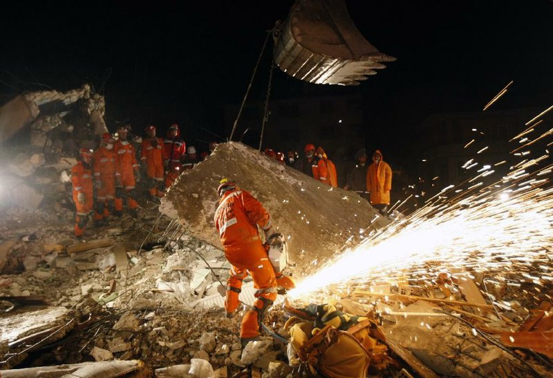 Rescuers work late Wednesday to reach people trapped in a collapsed building in Ercis, Turkey. 
