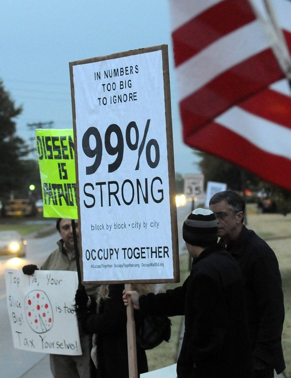 Demonstrators hold signs Thursday during the Washington County Lincoln Day Dinner at the Northwest Arkansas Convention Center in Springdale where Herman Cain was scheduled to speak. About 20 people associated with the OccupyNWA used the event to get their message out, noting they neither supported Cain nor protested his presence at the event.
