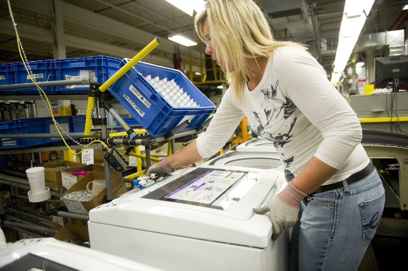 Tracy Harris attaches a lid to a top-load washing machine on the assembly line at the Whirlpool Corp. operations plant in Clyde, Ohio, on Thursday. Whirlpool said Friday that it expects job cuts and relocations to save it $400 million by the end of 2013. 