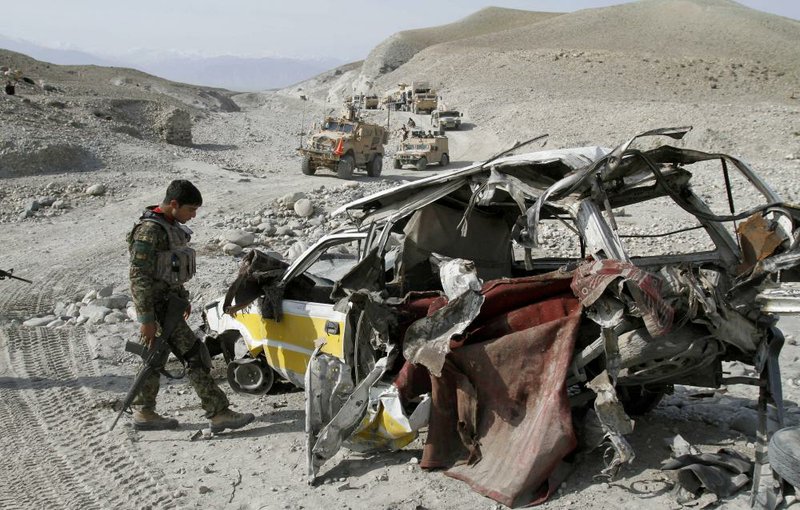 An Afghan security officer checks the wreckage of a vehicle Friday after it struck a roadside bomb east of Kabul. 